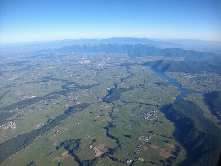 An aerial view of a picturesque landscape from high above, showing fields, rivers, and distant mountains, emphasizing the unique perspective of skydiving.